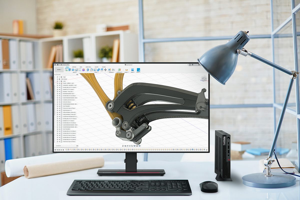 A Lenovo ThinkStation beside a widescreen monitor on an office desk, running CAD software on a bicycle frame design